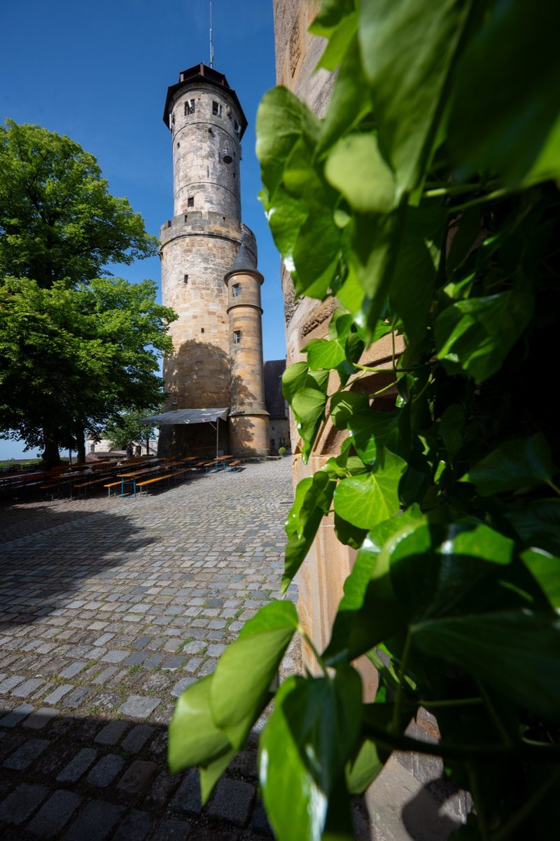 Der Bergfried von unten, davor Biergartenbänke.