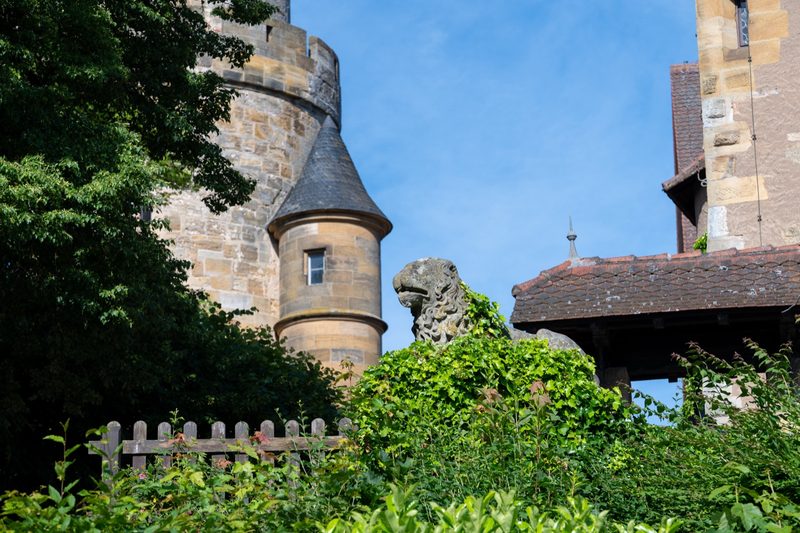 Efeuumranktes Löwenstandbild vor dem Bergfried.