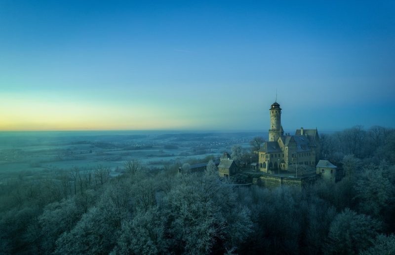 Blaue Stunde über der raureifbedeckten Landschaft, die Burg rechts auf ihrer Kuppe, im Westen das erste Morgenglühen über der weiten Ebene. 21. Dezember 2021.