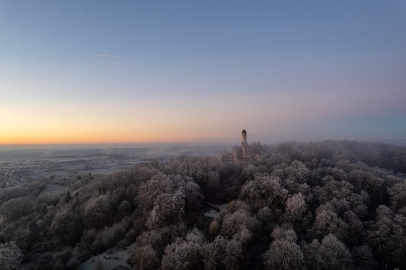 Die Burg im Morgennebel auf der bereiften Bergkuppe, links der glühende Sonnenaufgang über dem Maintal. 21. Dezember 2021.