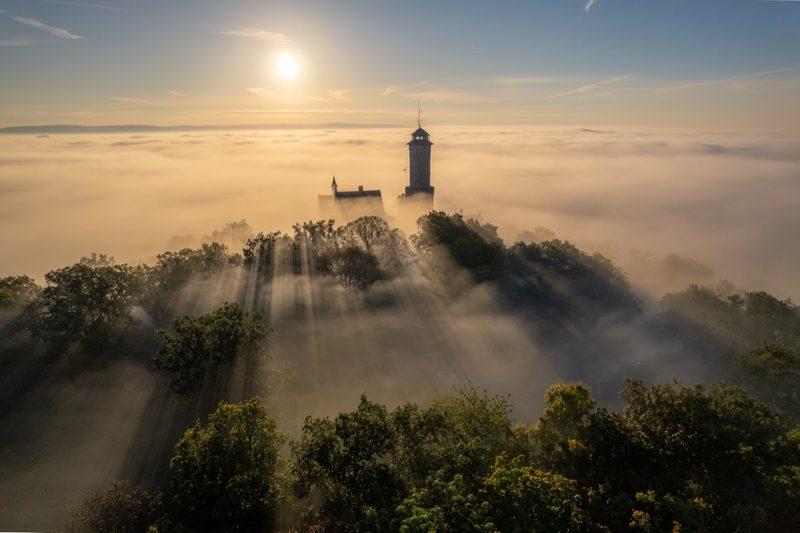 Sonnenaufgang über dem Nebelmeer: die Altenburg als Silhouette, das Morgenlicht in aufgefächerten Strahlen durch den Hochnebel. 30. September 2022.