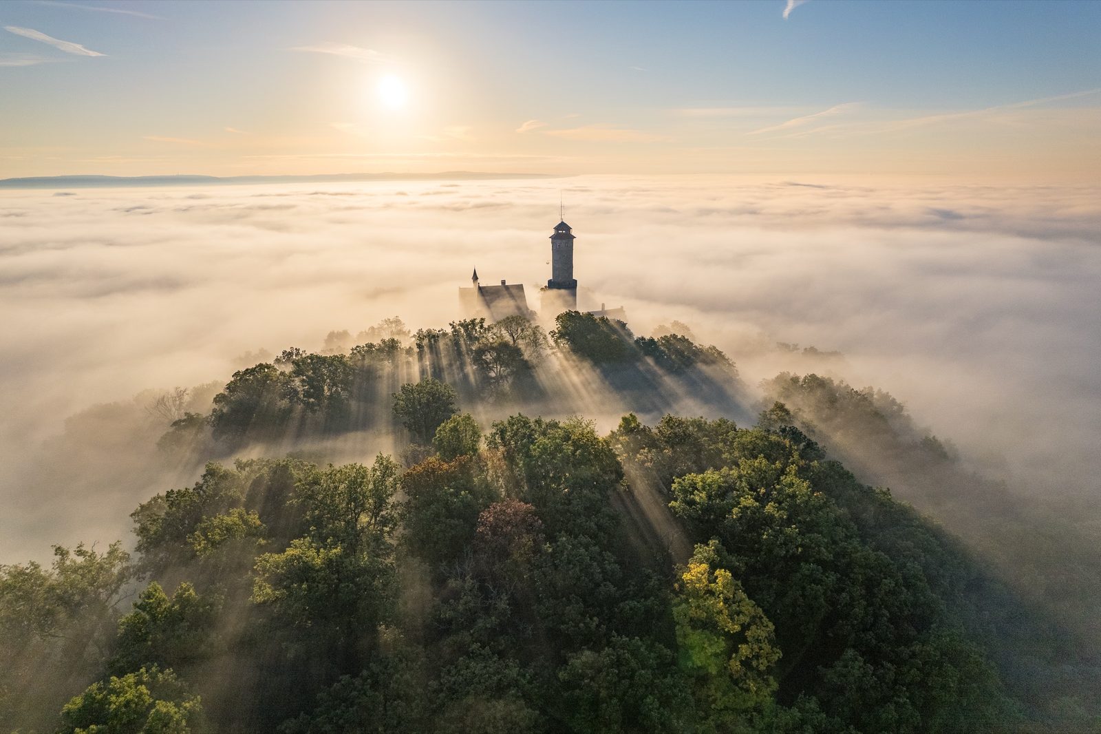 Luftaufnahme der Altenburg ob Bamberg über einem Nebelmeer, Sonnenstrahlen brechen durch den Wald am Burgberg